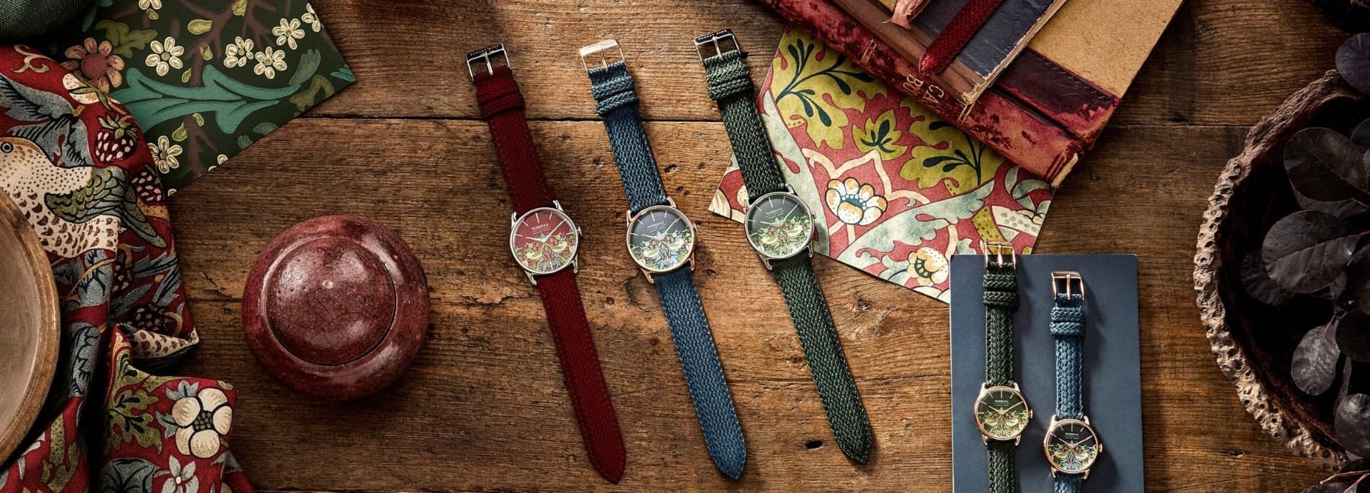 Morris & Co. x August Berg — five woven straps arranged across a wooden surface with floral textiles