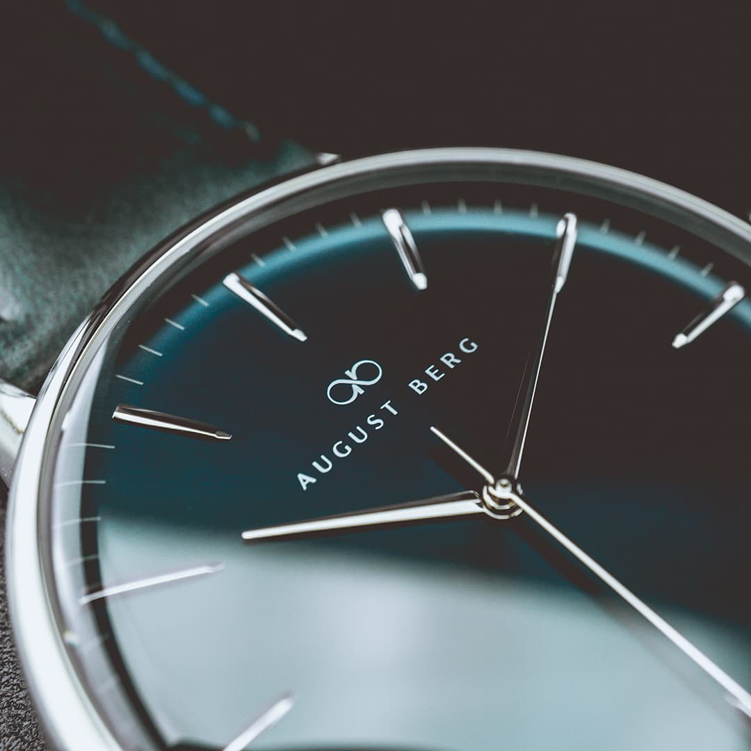 August Berg watch — close-up of a deep blue dial with polished steel case and navy leather strap